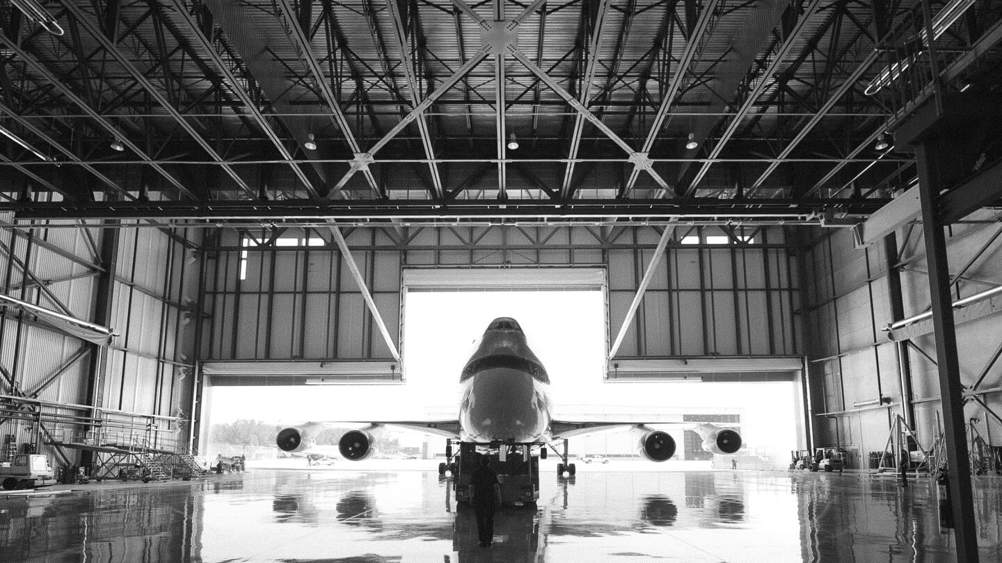 Paquette Électrique, réalisation Pratt & Whitney, hangar industriel pour aviation, avion à l'intérieur, structure métallique visible.